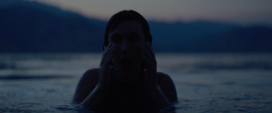 A woman rises up out of the water at dawn