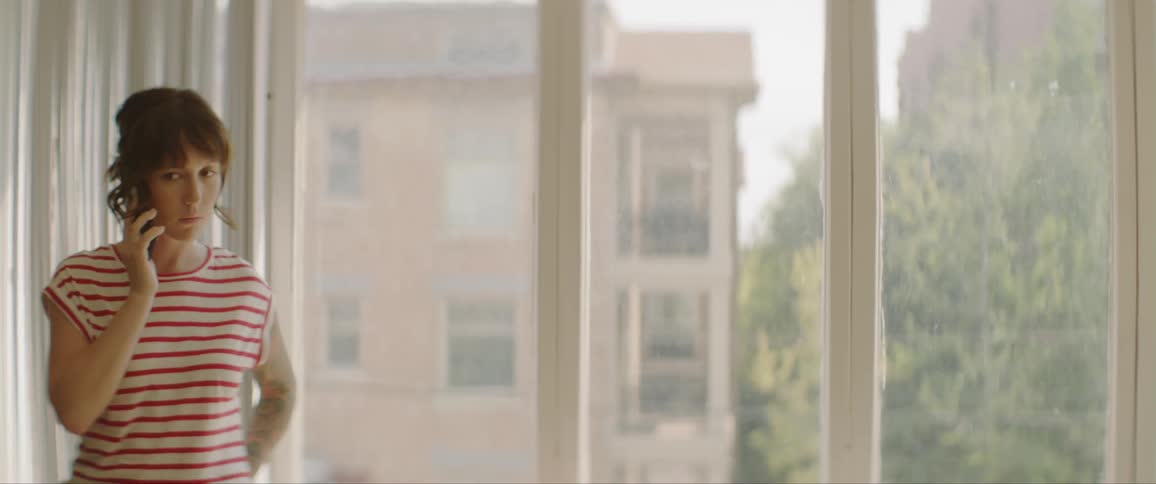 Young woman talking on cell phone in a room with many windows