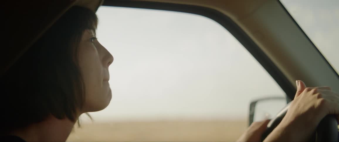 Young woman driving car nodding and tapping on steering wheel to music