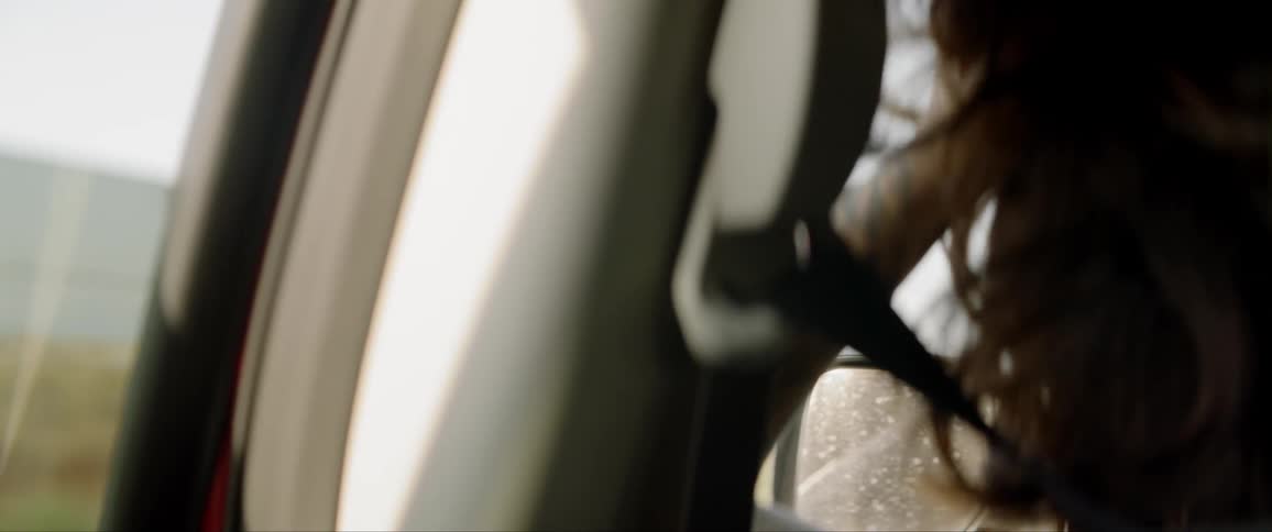 Person wearing seat belt stares out open window in vehicle