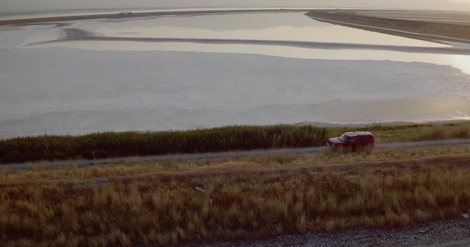 A vehicle drives a long a road next to a lake