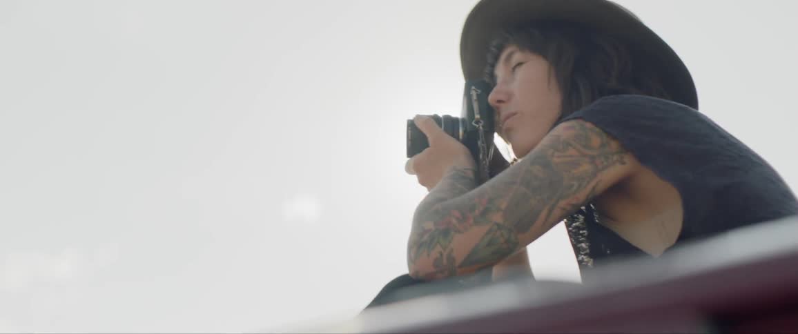 Photographer with tattoos takes picture under sunny sky