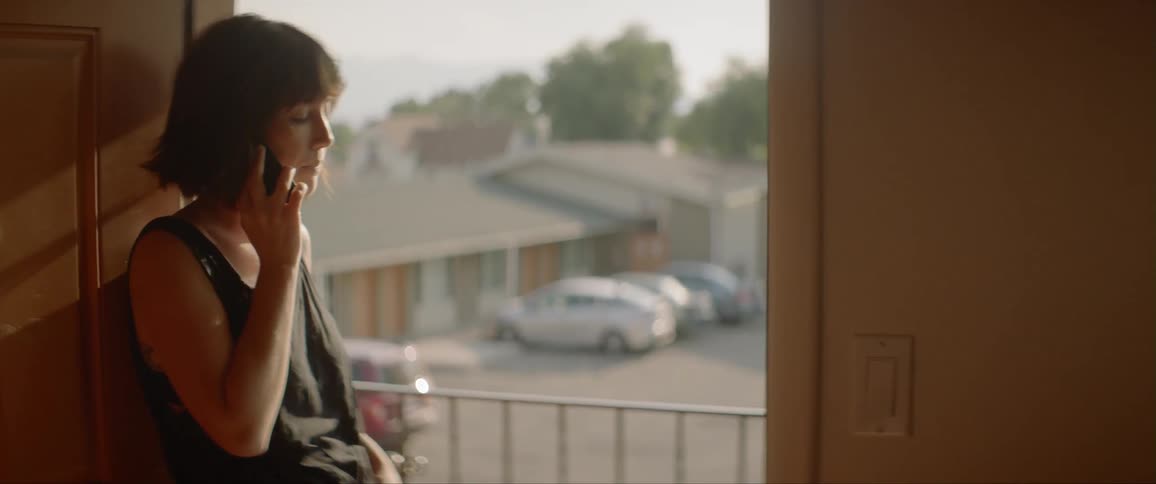 A woman stands in a doorway and talks on a cell phone