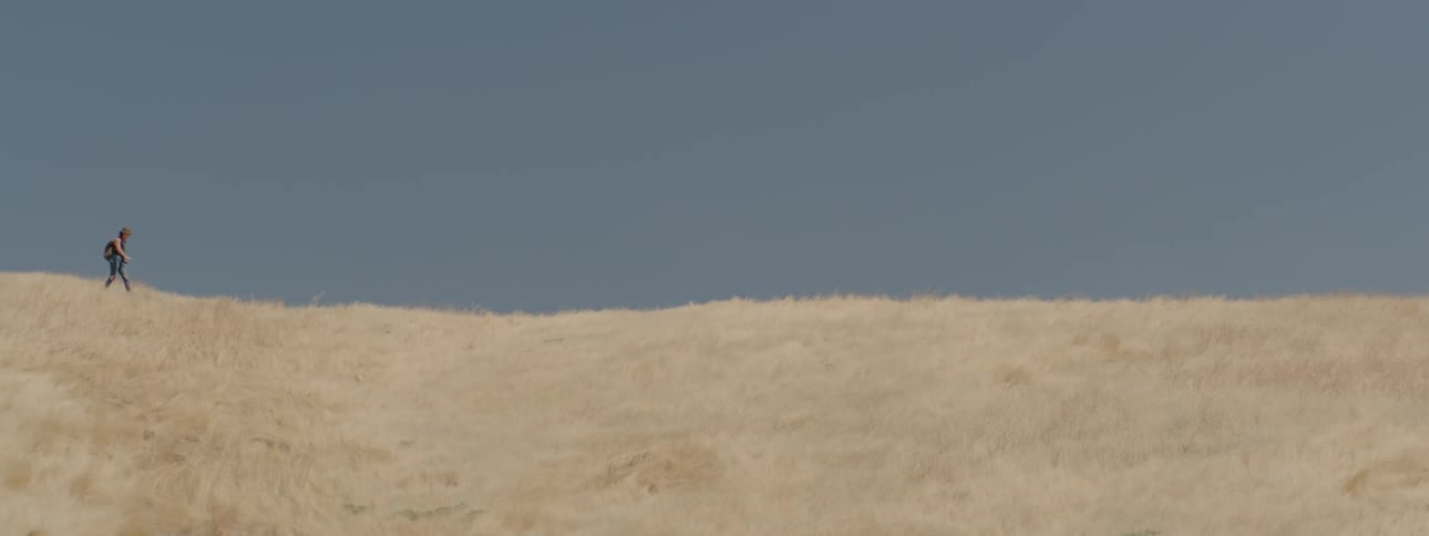 Male hiking in the distance on a hill in the country
