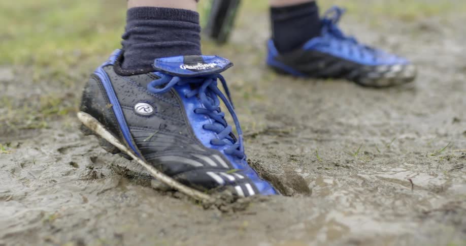Person wearing cleats twisting their foot in the mud