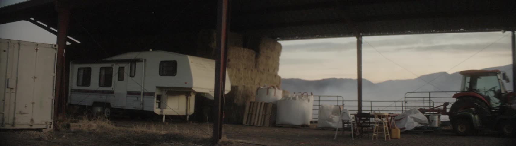Trailer house parked on a farm storage area near tractor