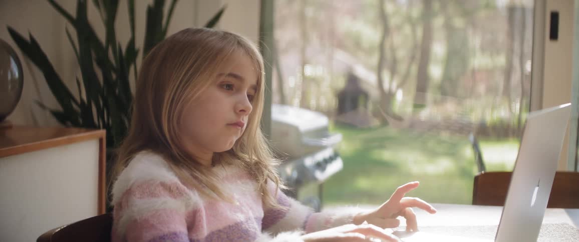 A young girl works on a laptop