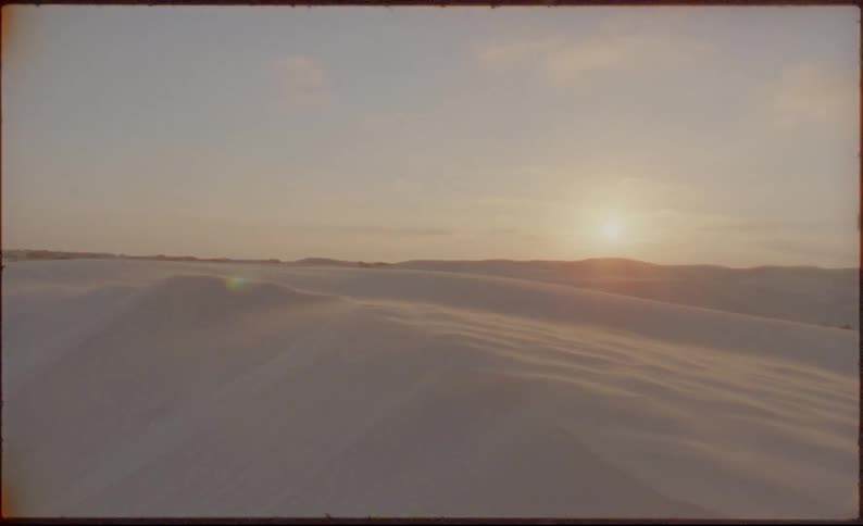 The sun sets over sand dunes in a desert