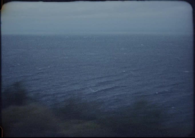 Road bordered on one side by cliff overlooks ocean on cloudy day