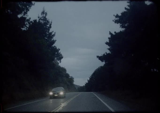 Headlights from an oncoming car shine and glow as the car passes