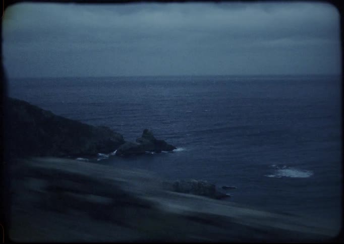 A car is driving on a road near the ocean coast