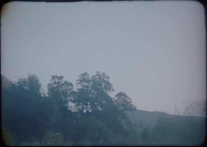Vintage footage of mountains and trees filmed from a moving car at sunset