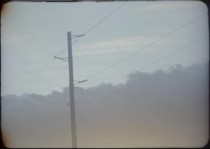 Clouds float above a power line at sunset