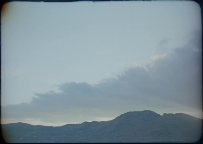 Clouds float above hills in a fog