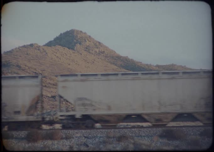 Vintage footage of freight train passing in front of mountain
