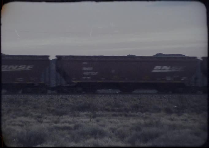 Train travels down the tracks in a field