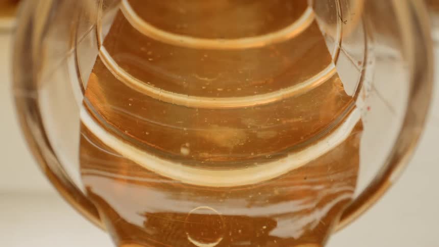 Honey pouring out of a glass container