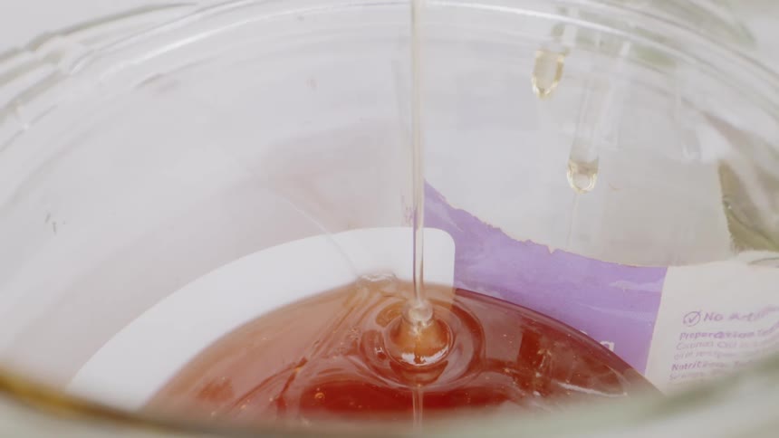 Honey is poured into a glass bowl