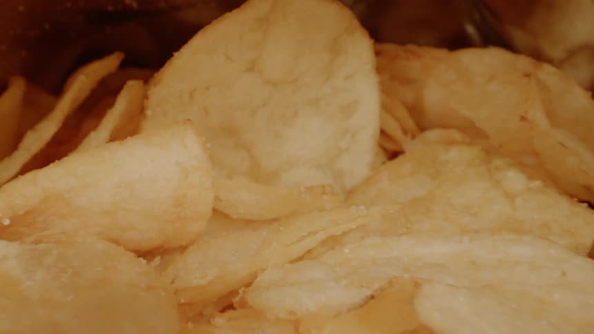 Hands open up a bag of potato chips