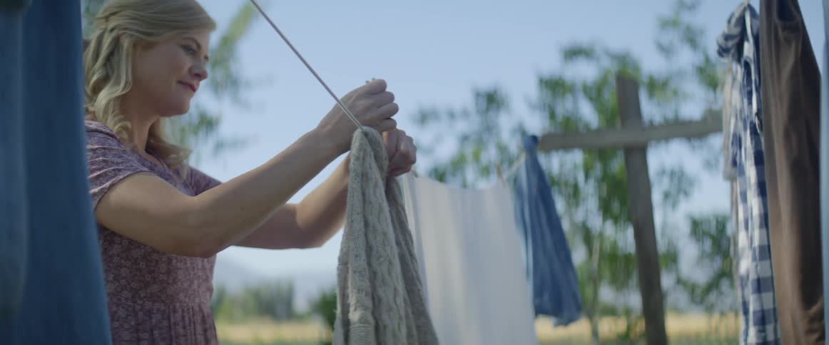 A woman hangs laundry on a clothesline outside