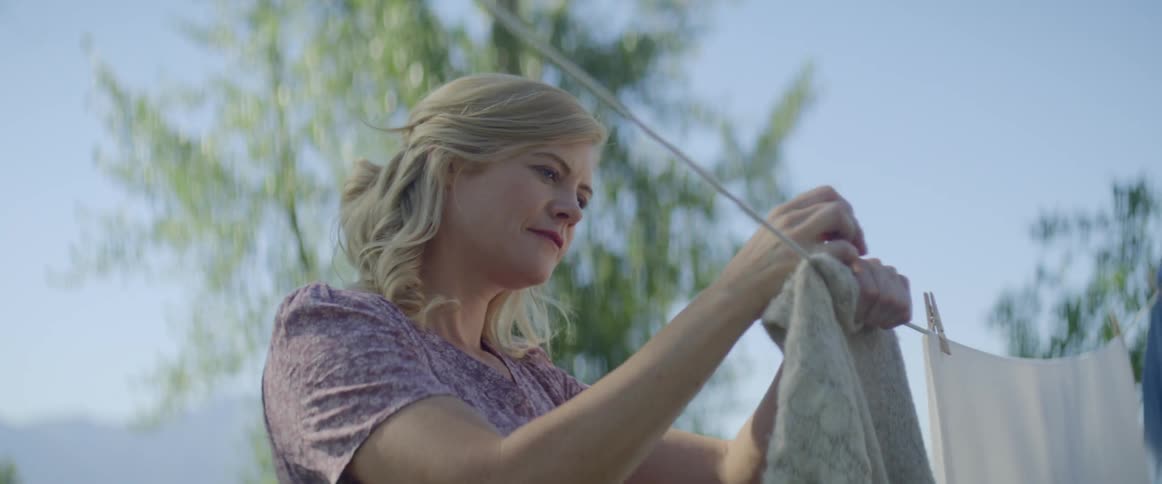 A woman holds up laundry on a line outside