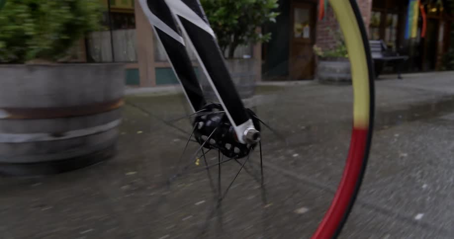 A person rides their bike on the sidewalk on a rainy day