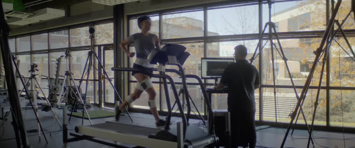 A man is watching a monitor as a woman runs on a treadmill