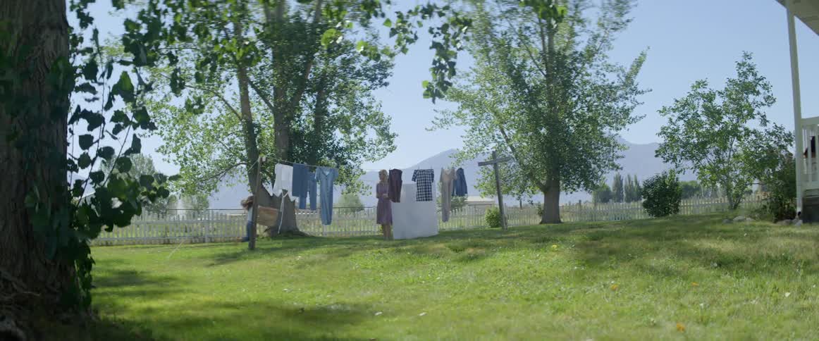 Mother and daughter hang wet clothes to dry outdoors