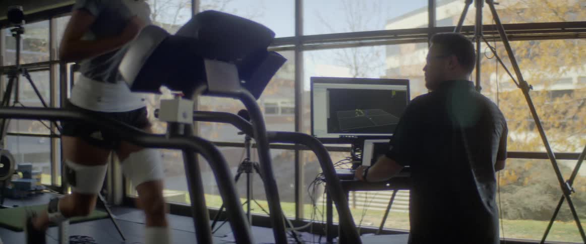 A man is monitoring a person running on a treadmill