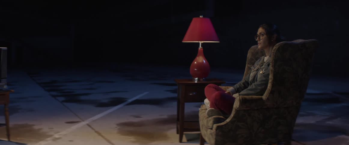 A woman sits cross legged in an armchair