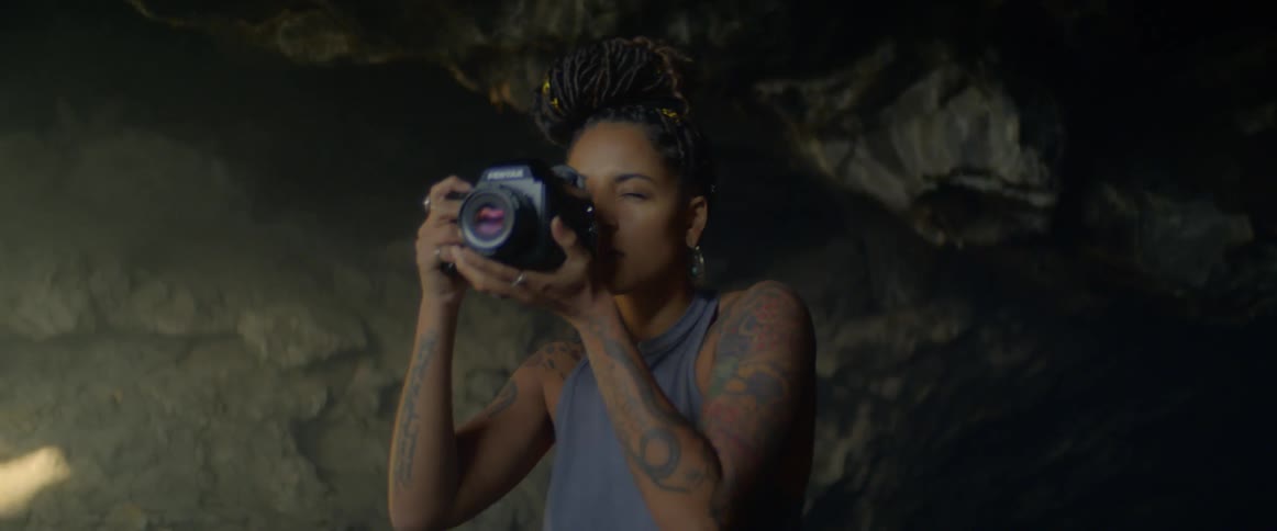 A young black woman takes photos in a cave