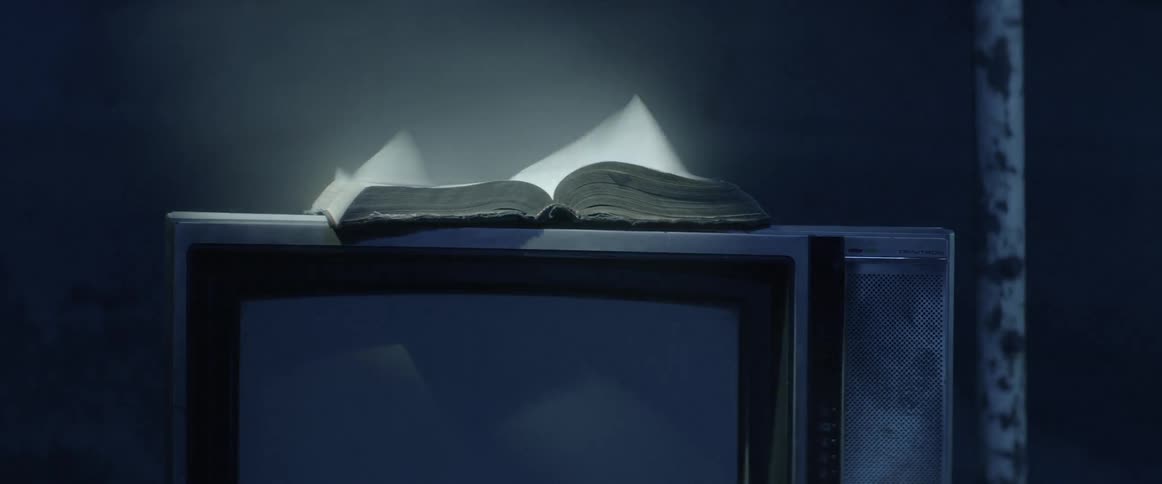 Wind blows pages of book an fog past television set