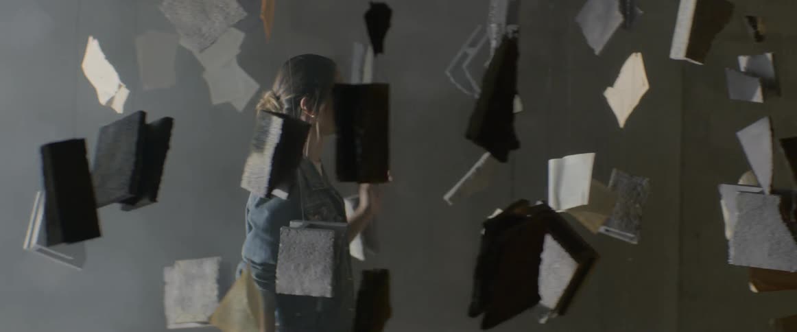 Woman walking through art installation with books hanging from wires