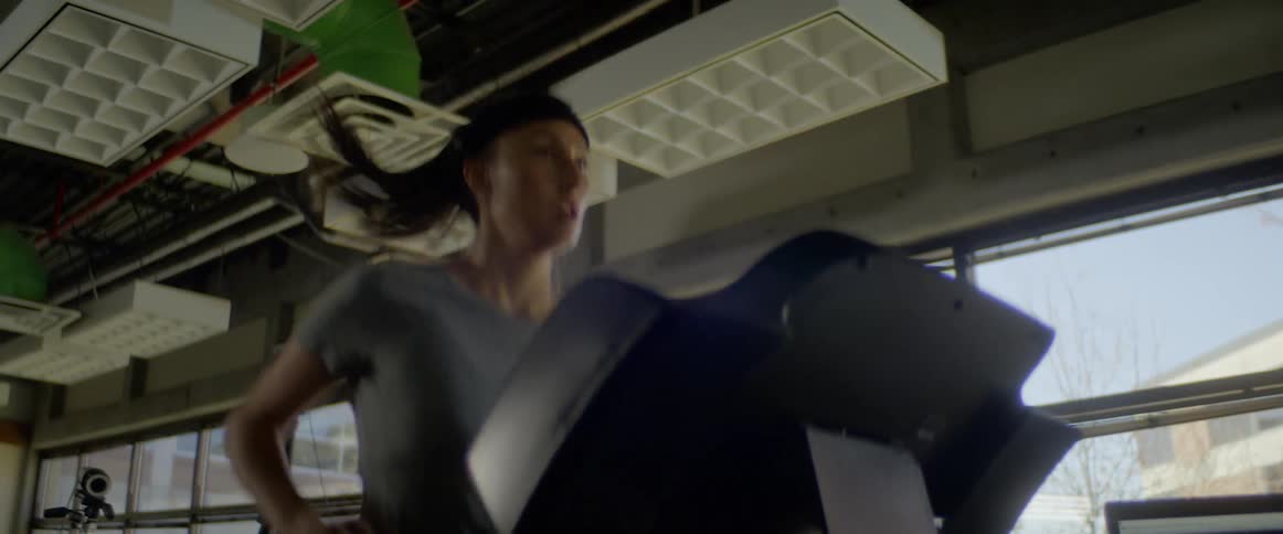 Woman runs on a treadmill as a man stands nearby looking at a monitor