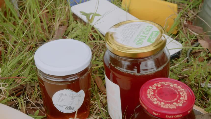 Canned containers of jelly laying on grass outdoors