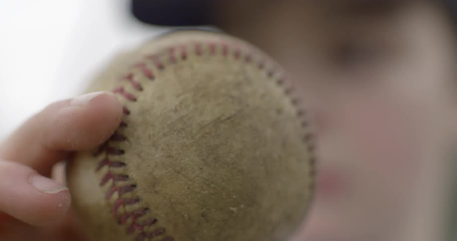 Someone holds a baseball in their hand