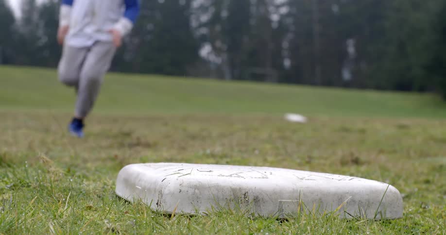 A boy runs around a baseball field on a rainy day