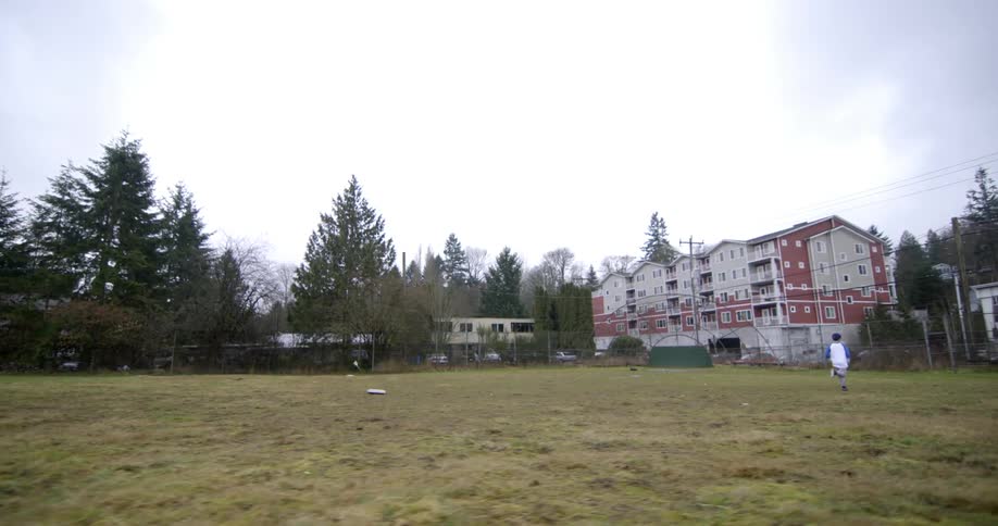 A boy is running in a field on a cloudy day