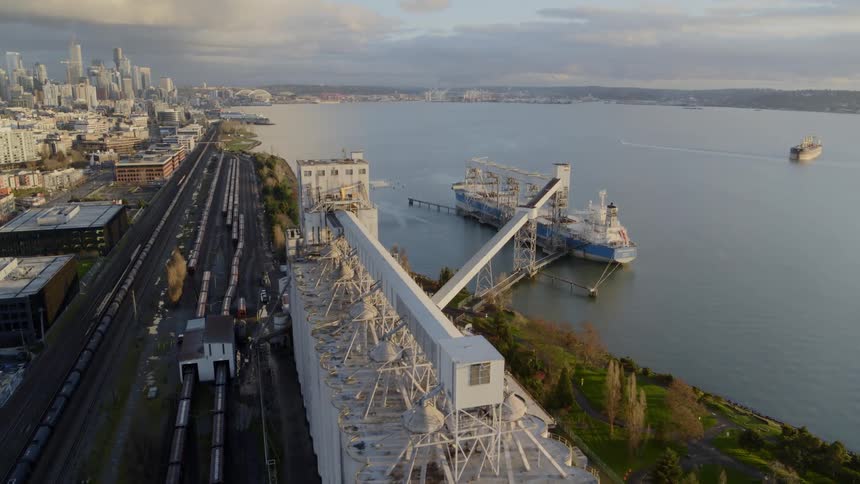 A large cargo ship is docked at a port shipping facility near a city