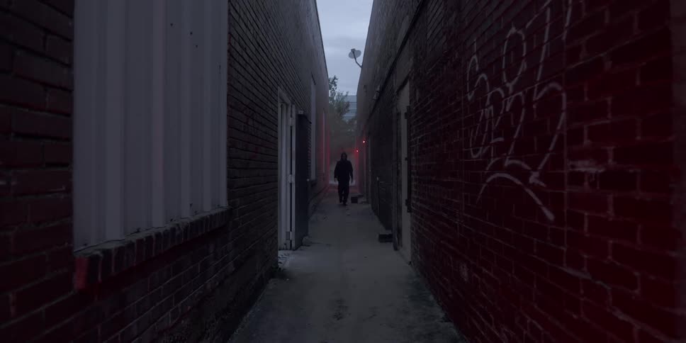 A man walks down a graffiti covered alleyway