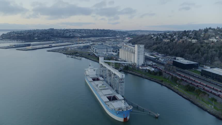 The cargo holds of a large freighter are filled while docked at a grain terminal facility