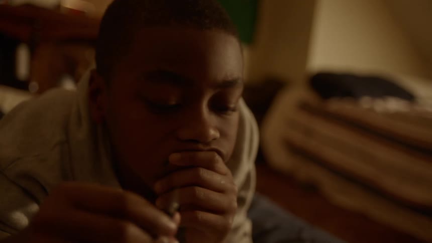 A boy plays with a pen in his hand while lying on the ground