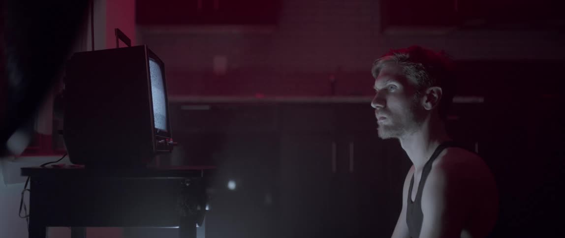 A man stares at a small television playing nothing but static