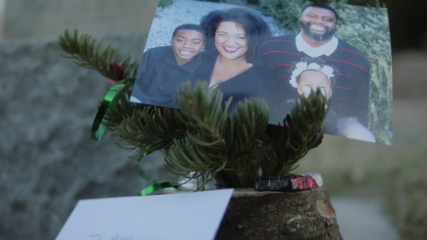 A card and picture of a family sits on a memorial plant