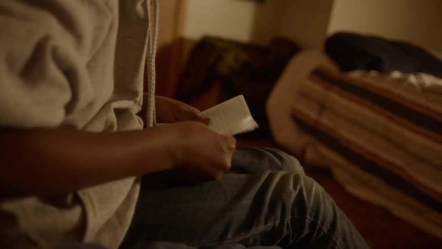A teenager folds a piece of paper in half and stands up