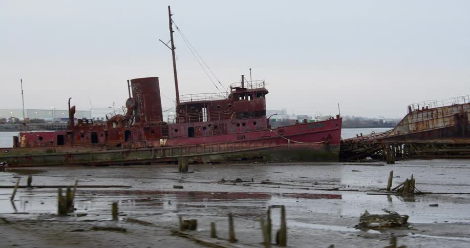 An abandoned ship floats just off a shoreline