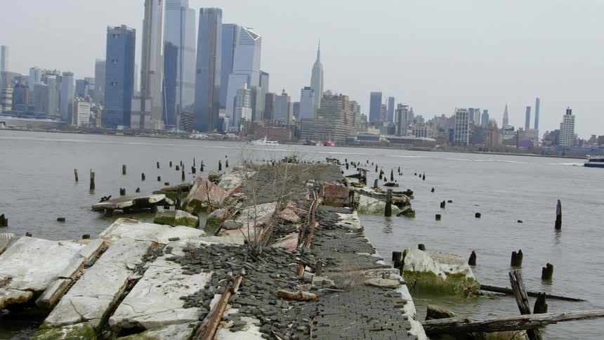 Wrecked pier stands across water from downtown city