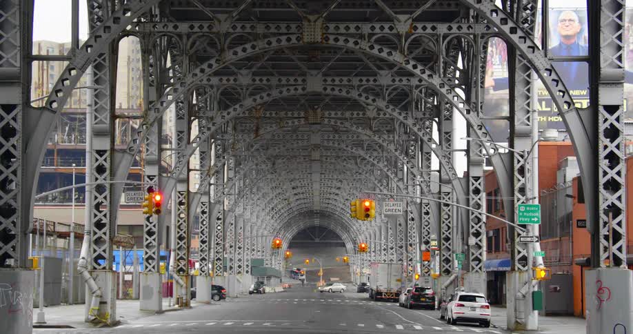 Vehicles drive on a road under an arched bridge