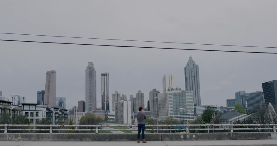 A man stands in front on a city skyline on an overcast day