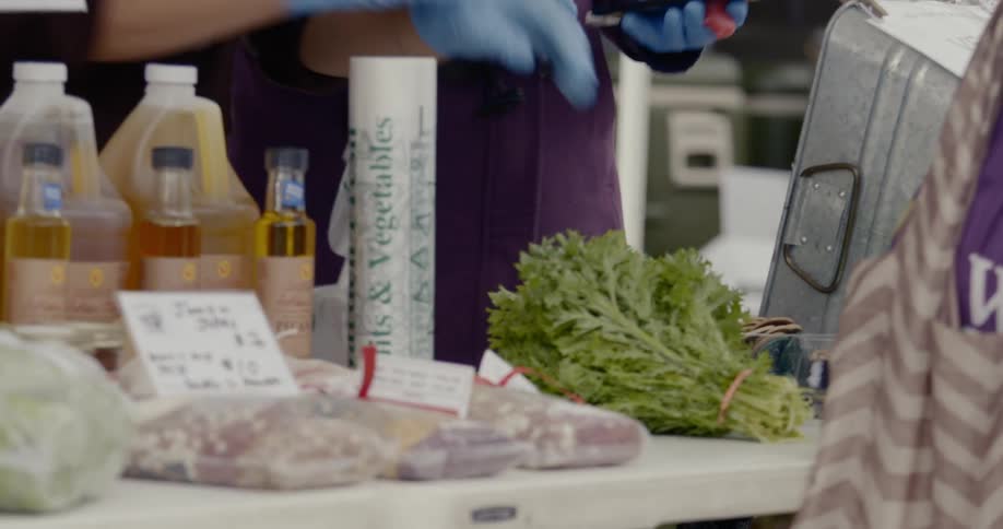 A woman sets down a bundle of herbs at a farmers market